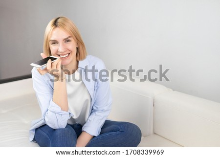 Woman holds phone talks on speakerphone, makes voice recognition or request uses internet services through virtual assistant, record audio message. Copy space