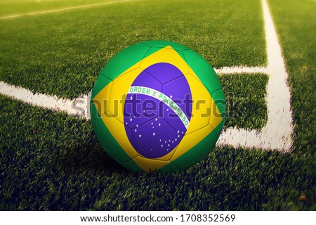 Brazil flag on ball at corner kick position, soccer field background. National football theme on green grass.