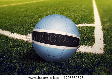 Botswana flag on ball at corner kick position, soccer field background. National football theme on green grass.