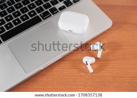 Air Pods Pro. macbook. with Wireless Charging Case. New Airpods pro on wooden background. Airpods. Copy space Royalty-Free Stock Photo #1708357138