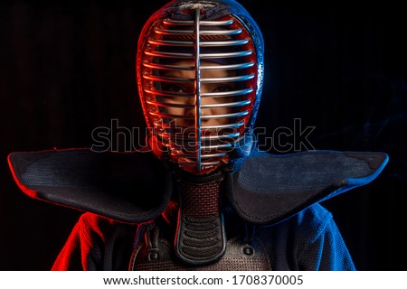 portrait of kendo fighter in uniform and protective helmet. combat warrior isolated over neon lighted space