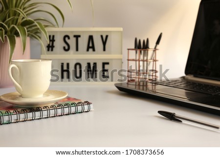 Home office  desc concept during self quarantine as preventive measure against virus. Stay safe concept. Cup of coffee, laptop, clock, stationary, home plant on white background Royalty-Free Stock Photo #1708373656