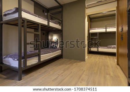 Modern, luxury, hostel, dorm, dormitory, motel room. Wooden floor room full of comfortable beds. Accomodation for students. Bedroom view from a hostel. Royalty-Free Stock Photo #1708374511