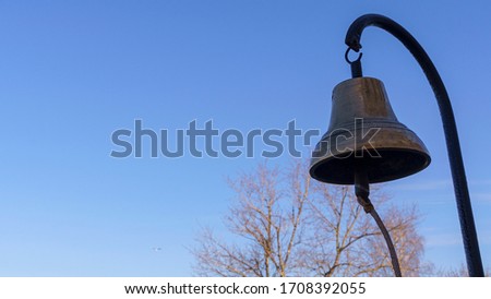 Old skool bronze fire bell on the classic blue sky background. Alarm fire concept.