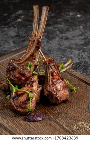 Grilled lamb ribs on cutting board. Hot rack of lamb with spices and condiments. Top view on wooden table Royalty-Free Stock Photo #1708423639