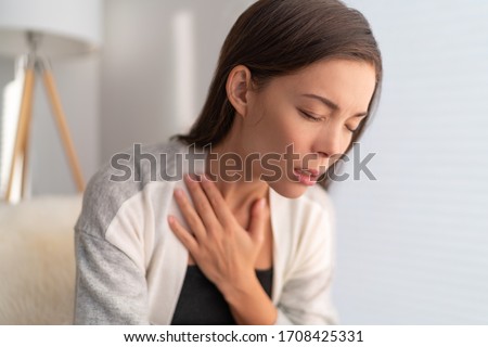 COVID-19 breathing difficulties woman with shortness of breath Coronavirus cough breathing problem. Asian girl in pain touching chest respiratory symptoms fever, coughing, body aches. Royalty-Free Stock Photo #1708425331