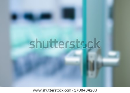 glass door in an open office room in a business center against a white wall. Business space with a glass door and a metal handle. Blurred image as background for business