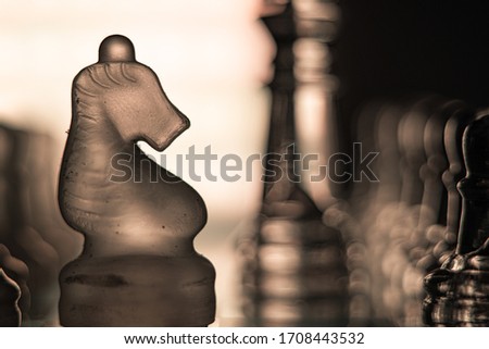 Knight chess piece in the middle of a chessboard illuminated by a tender white