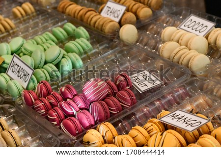 multicolored dessert macarons at the local sweet market. white signs in Italian and English indicate the taste of macarons