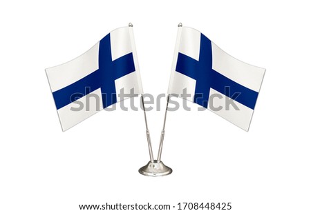 Finland table flag isolated on white ground. Two flag poles with flags and Finland flag on the table.
