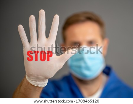 COVID-19 Outbreak. Male Doctor or nurse wearing face surgical mask and gloves PPE showing hand in STOP gesture. Help to stop the virus spread campaign visual support.