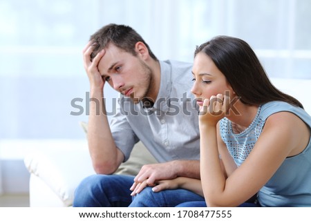 Sad worried couple complaining together holding hands on a couch at home Royalty-Free Stock Photo #1708477555