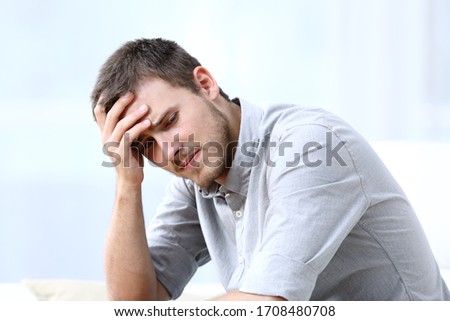 Sad worried man complaining sitting alone on a couch at home Royalty-Free Stock Photo #1708480708