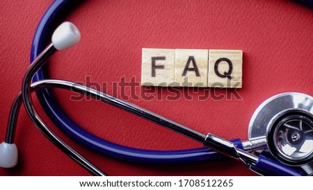 Wording of wooden FAQ surround by blue stethoscope against red background. Medical Frequently Ask Question concept. 