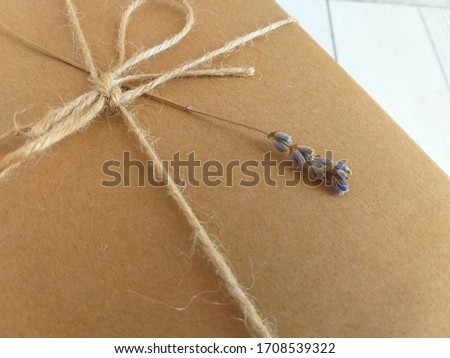 Gift cardboard box closeup tied with a rope with lavender on a light wooden background. Box for postcard text.