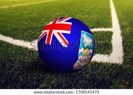 Falkland Islands flag on ball at corner kick position, soccer field background. National football theme on green grass.