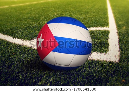 Cuba flag on ball at corner kick position, soccer field background. National football theme on green grass.