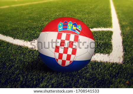 Croatia flag on ball at corner kick position, soccer field background. National football theme on green grass.