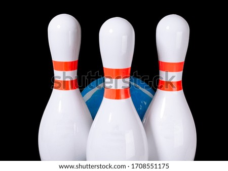 Bowling pins of white color isolated on black background. Blue bowling ball