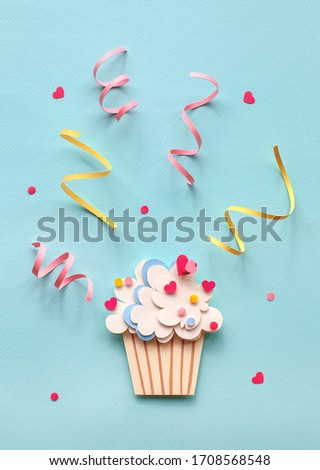 Handmade paper art and cutout cupcake on blue background. With colorful sprinkles. Cartoon style. 