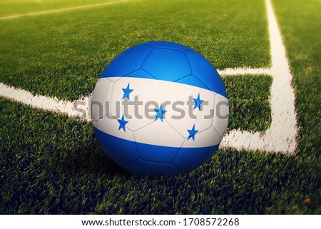 Honduras flag on ball at corner kick position, soccer field background. National football theme on green grass.