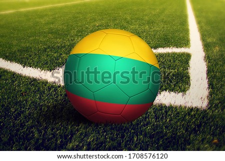 Lithuania flag on ball at corner kick position, soccer field background. National football theme on green grass.