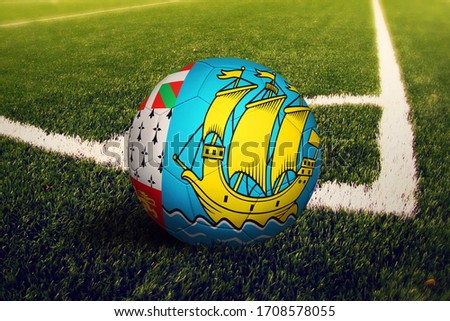 Saint Pierre And Miquelon flag on ball at corner kick position, soccer field background. National football theme on green grass.
