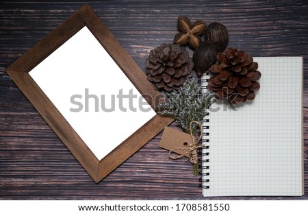 Blank grid-lined notebook and picture frame decorated with small dried flower bouquet and dried pine cone, sacha inchi, foxtales palm