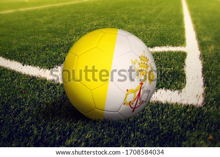 Vatican City flag on ball at corner kick position, soccer field background. National football theme on green grass.