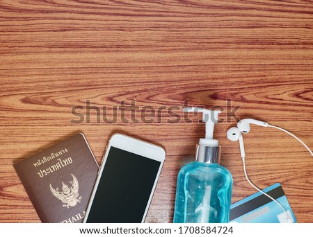 Top view picture of Thailand passport with smartphone,alcohol gel,credit card and Headphones on wood table background.