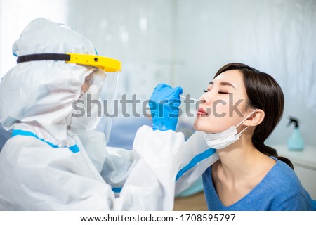 Coronavirus test - Medical worker taking a swab for corona virus sample from potentially infected woman with the isolation gown or protective suits and surgical face masks Royalty-Free Stock Photo #1708595797