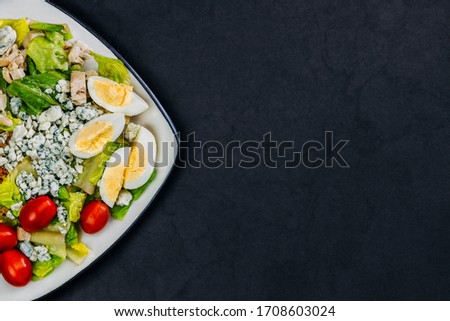 Organic homemade salad. Great photo for food menu. Assorted vegetable salad with tomatoes, eggs, bacon, french cheese Roquefort, chicken meat, lettuce. Royalty-Free Stock Photo #1708603024