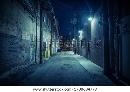 Dark and eerie urban city alley at night Royalty-Free Stock Photo #1708604779