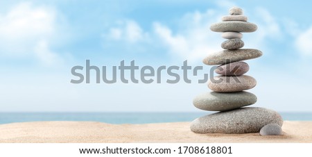 Pyramid of sea pebbles on a sunny sand beach. Life balance and harmony concept Royalty-Free Stock Photo #1708618801
