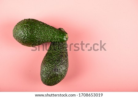 Two green avocadoes isolated on pink background