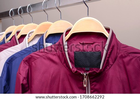 Row of many different colorful hoodie jackets, sport jackets for men and women. Colorful background of modern spring, autumn outerwear. New collection. Seasonal clothing in store on sale.