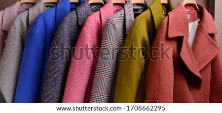 New collection of different color autumn's women's wear in shop. Fur and wool coats on hanger. Colorful background of modern spring, autumn outerwear. Close up. Seasonal clothing in store on sale. Royalty-Free Stock Photo #1708662295