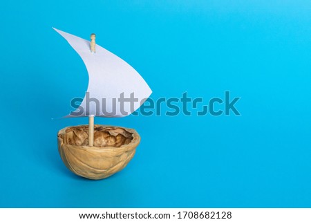 a boat made of nutshell with a white sail on the blue background. Journey banner template. Royalty-Free Stock Photo #1708682128