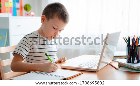 Distance learning online education. A schoolboy boy studies at home and does school homework. A home distance learning. Royalty-Free Stock Photo #1708695802