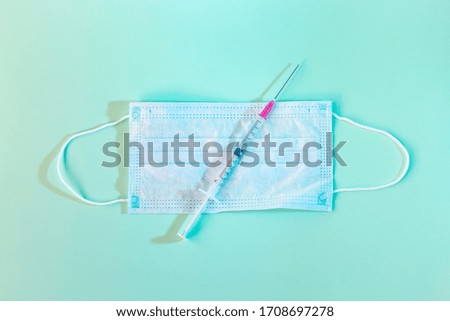vaccine or injection on a medical mask on blue background. Cure and health care concept.