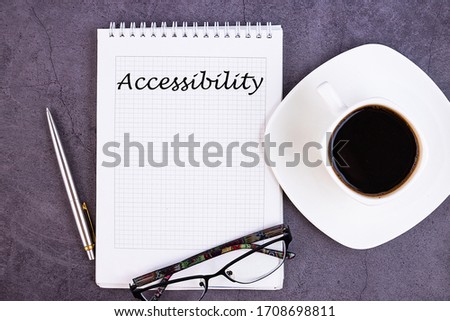 The inscription, the phrase Accessibility is written in a notebook that lies on a dark table with a cup of coffee and pen and glasses. Business concept.