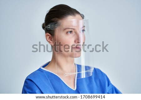Close up portrait of female medical doctor or nurse wearing face shield Royalty-Free Stock Photo #1708699414