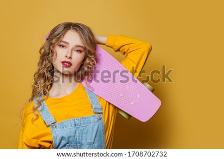 Girl with skateboard on bright yellow background