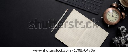 Overhead shot of dark concept office desk with blank notebook, digital device and decoration one black table 