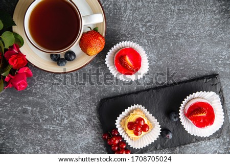Top view on hot black tea in a cute cup with strawberry dessert, horizontal