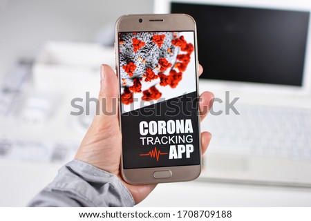 Corona Virus Tracking App concept with hand holding cell phone with application design on screen in front of blurry office background Royalty-Free Stock Photo #1708709188