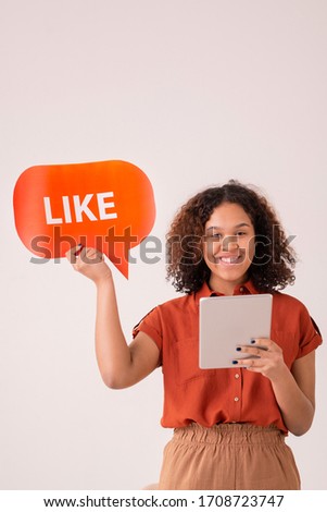 Portrait of smiling Afro-American girl with curly hair using digital tablet and liking post on social media