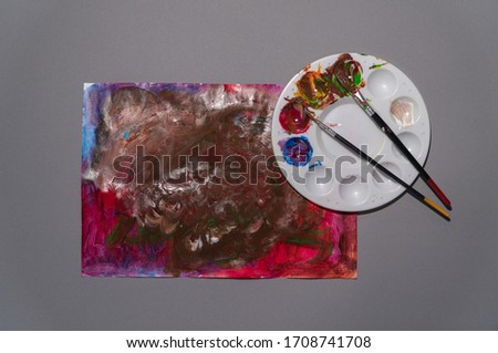 Being creative during quarantine concept a paint pallet placed next to abstract picture, top view