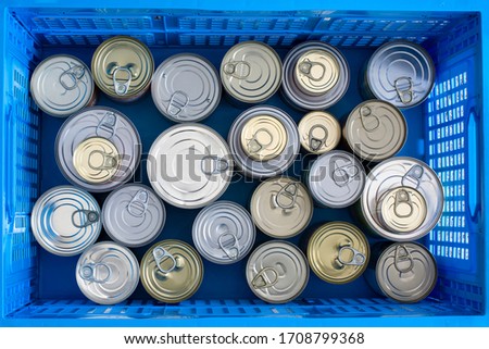 Lots of canned food in different sizes. Preserved food in collapsible crate grocery store packing container. Hoarding food as a quarantine stock from coronavirus. Stock of non-perishable foods Royalty-Free Stock Photo #1708799368