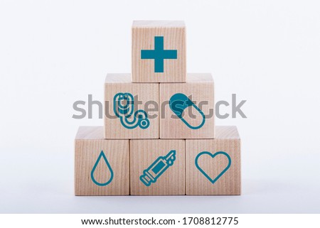 Medical symbols on wooden blocks stacked in a pyramid on white background. Medical and pharmaceutical concept. Medical treatment and public health problems.